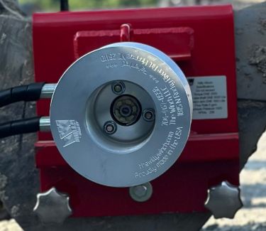 Closeup of aluminum capstan on red metal bracket