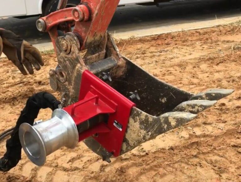 Red winch with aluminum capstan hitched to muddy excavator
